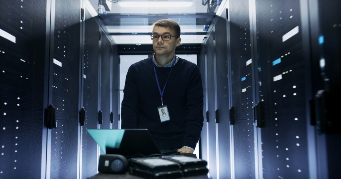A data engineer walking through a server room data center in 2026