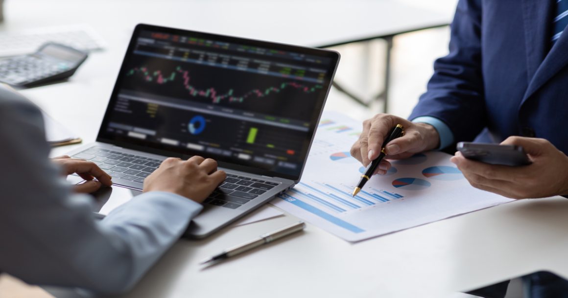 Two professionals collaborating on data analysis and machine learning metrics on a laptop during a business meeting.