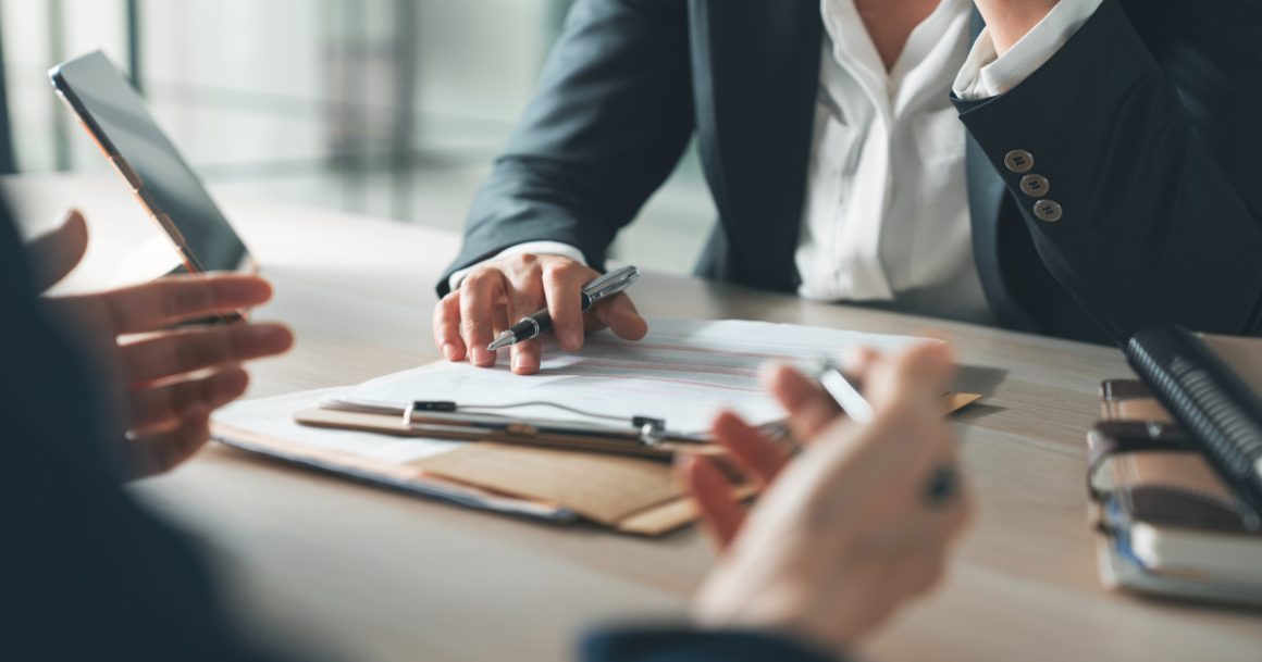 Interviewer and candidate reviewing documents across a desk during a job interview