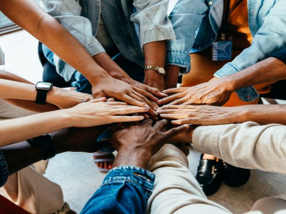 Diverse team stacking hands together in a circle to show teamwork and collaboration.