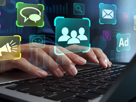 Hands on a laptop surrounded by digital marketing icons for email, ads, and social media.